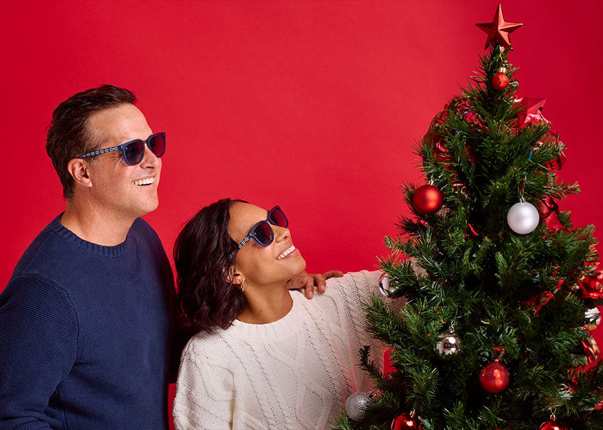 Man and Woman wearing Knockaround sunglasses while decorating a Christmas tree
