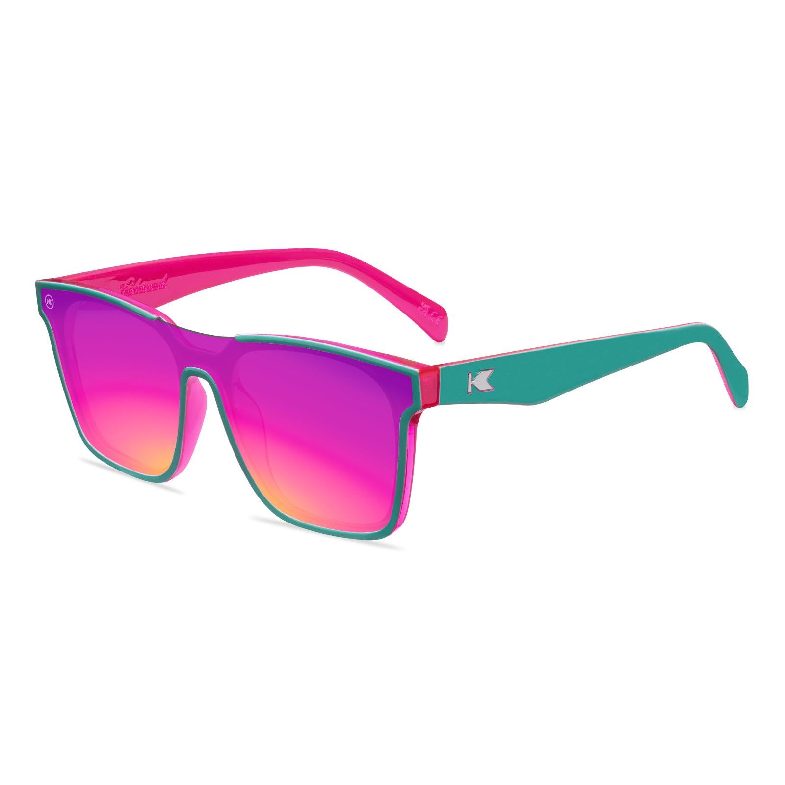Sunglasses with a teal and pink frame with polarized pink and purple lenses, flyover