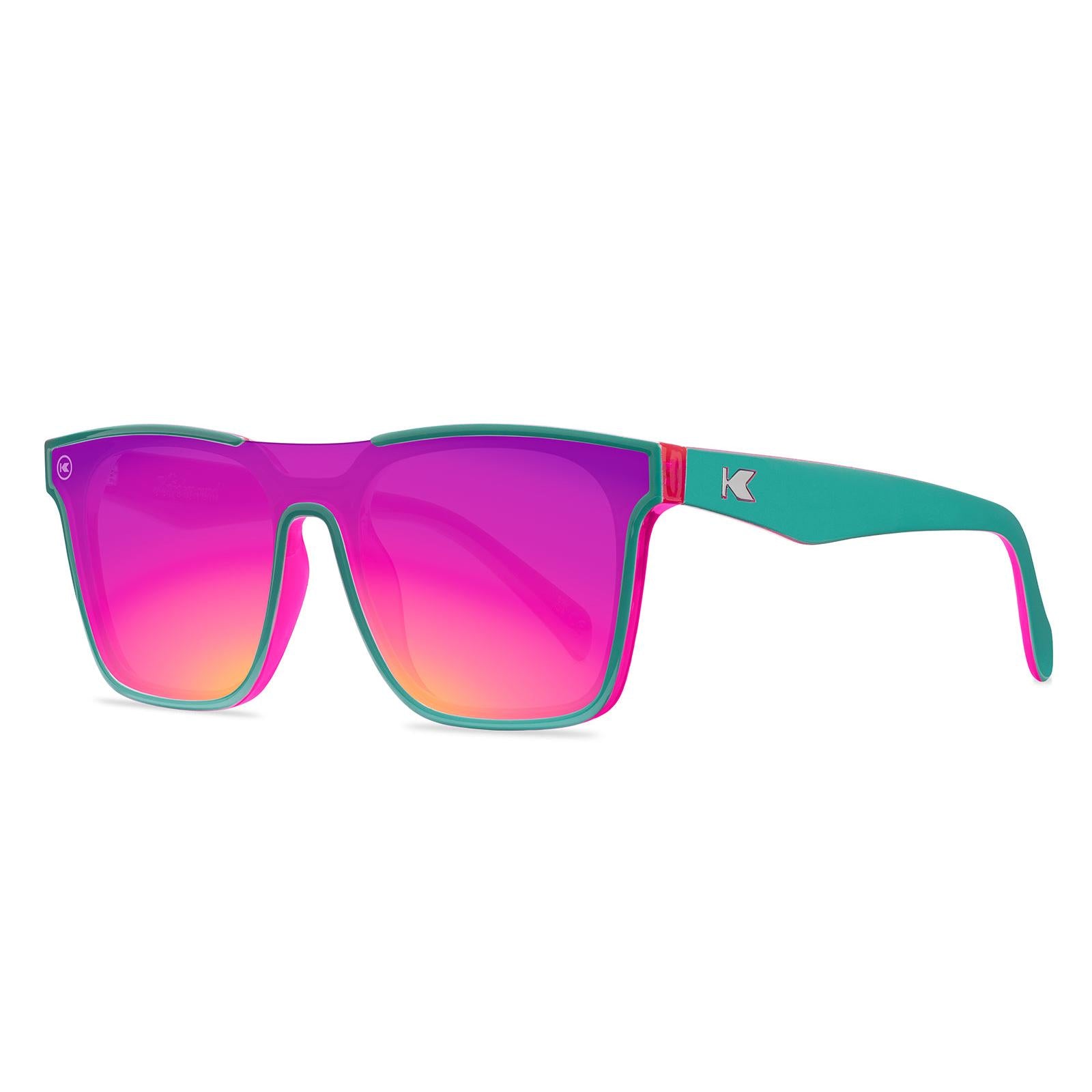 Sunglasses with a teal and pink frame with polarized pink and purple lenses, threequarter