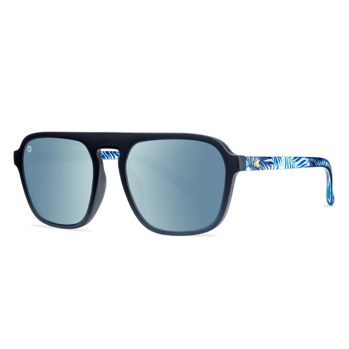 Sunglasses with black fronts, blue palm tree arms and polarized sky blue lenses, threequarter