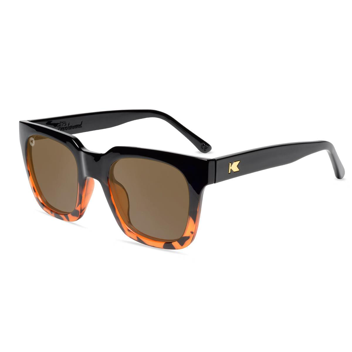 Sunglasses with a glossy black and tortoise shell frame with polarized amber lenses, flyover