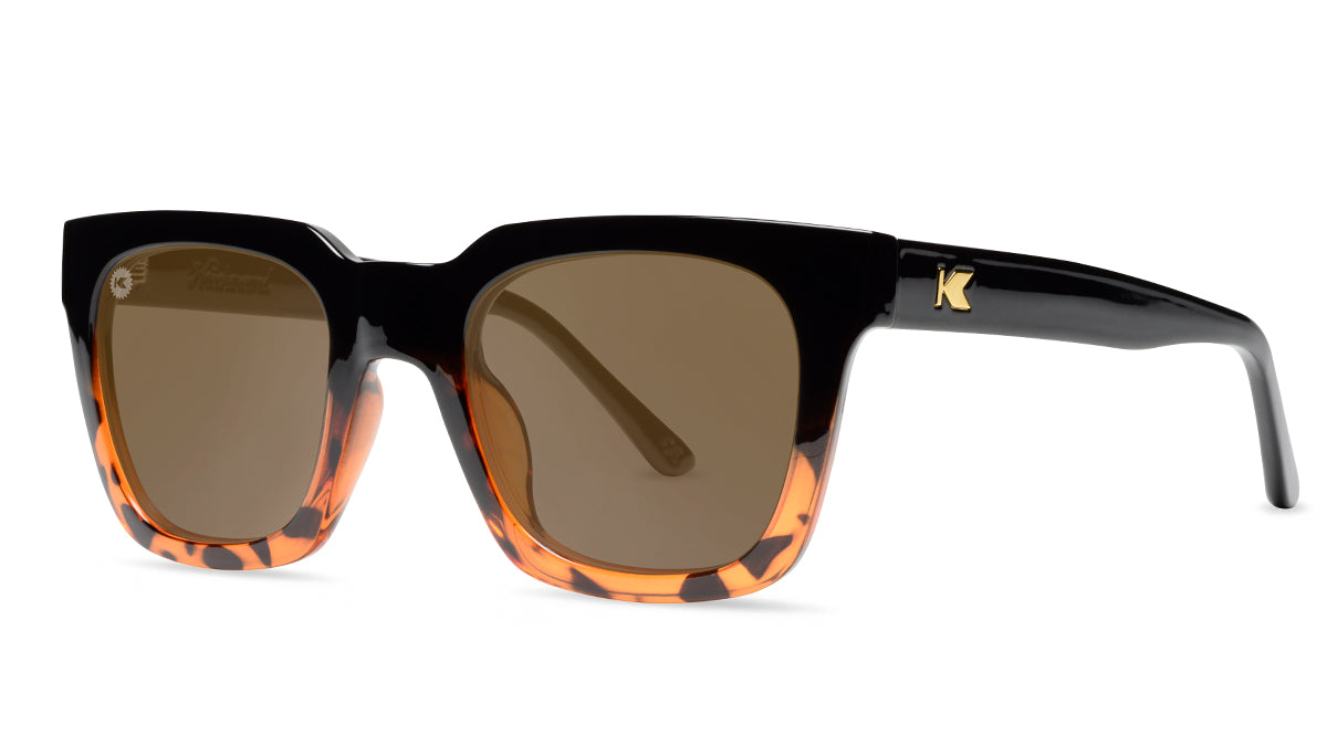 Sunglasses with a glossy black and tortoise shell frame with polarized amber lenses, threequarter