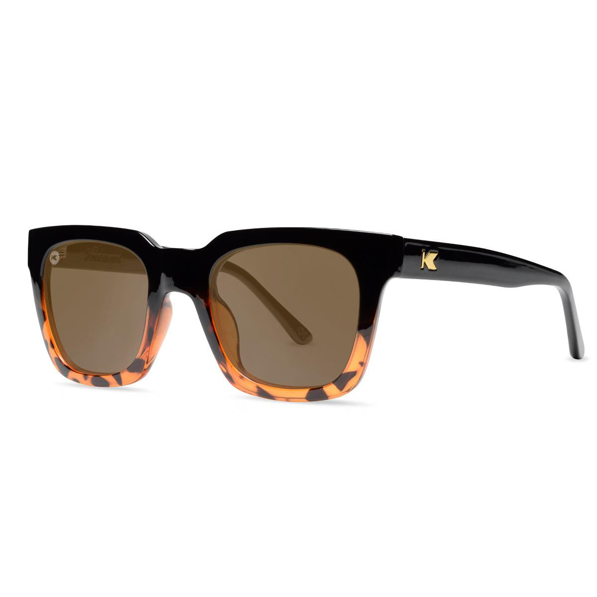 Sunglasses with a glossy black and tortoise shell frame with polarized amber lenses, threequarter