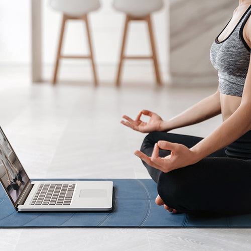 Woman sitting cross legged while doing virtual yoga