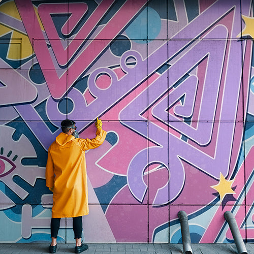 Street artist painting colorful graffiti on wall