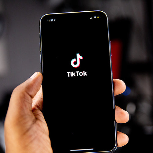 Hand holding smartphone with the TikTok app