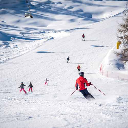 Skiers and a ski track on a sunny day in the Alps