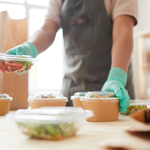 Food worker wearing gloves and packing takeout orders