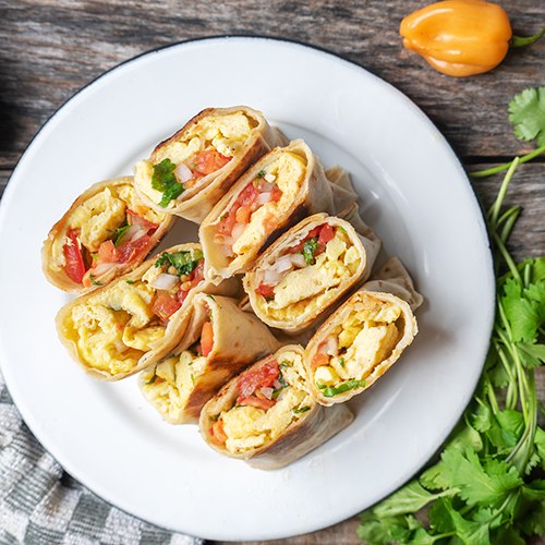 A plate of breakfast burritos on wooden background