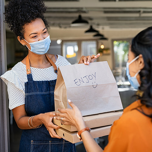 Woman wearing a mask delivering takeout food