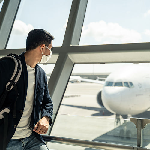 Man wearing a mask at the airport while looking at a plane