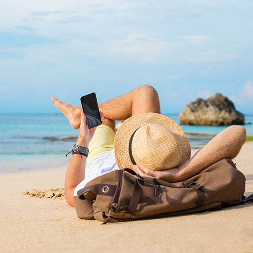 Guy with smartphone lying on the beach