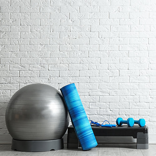 Set of fitness equipment on the floor near a white brick wall