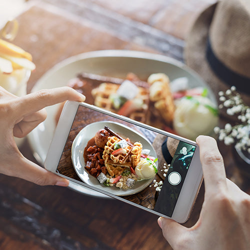 Person taking photo of food with smart phone in restaurant