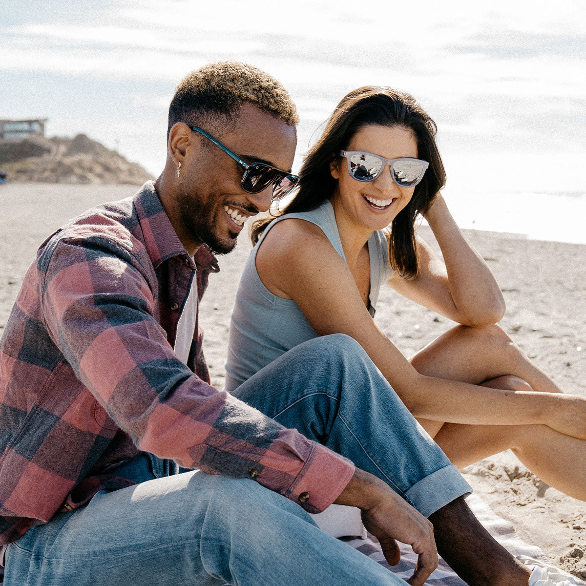 couple sitting on beach wearing sunglasses