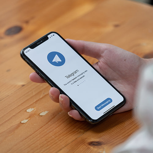 Hand holding a smartphone using the Telegram app