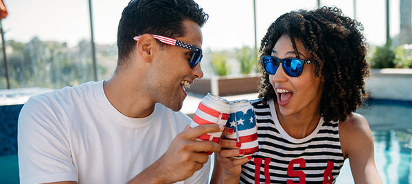 Couple by the pool cheering and wearing Star Spangled Knockaround sunglasses
