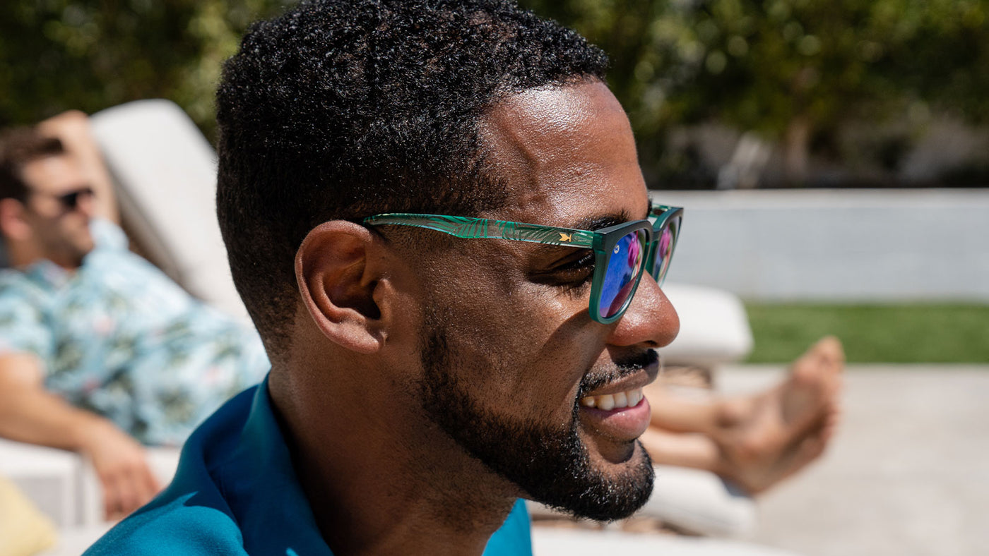 Sunglasses with green fronts, green palm tree arms, and polarized green lenses, model