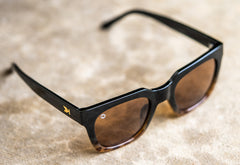 Sunglasses with a glossy black and blonde tortoise shell frame with polarized amber lenses, lifestyle