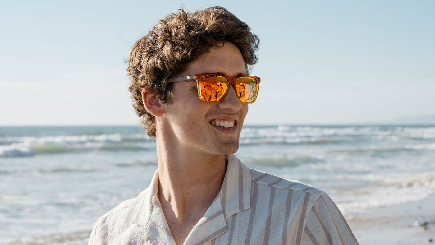 Man on the beach wearing orange sunglasses