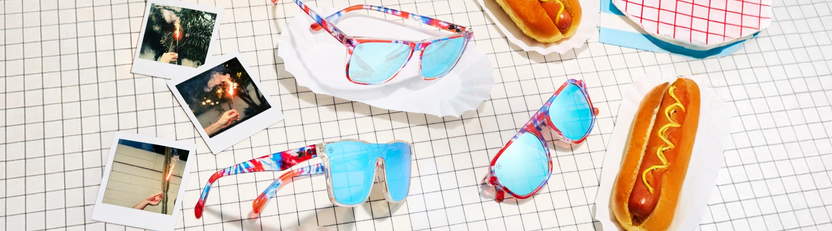Live Free or Tie Dye sunglasses available in Fast Lanes, Pacific Palisades, and Afters. Pictured with hot dogs on a picnic table