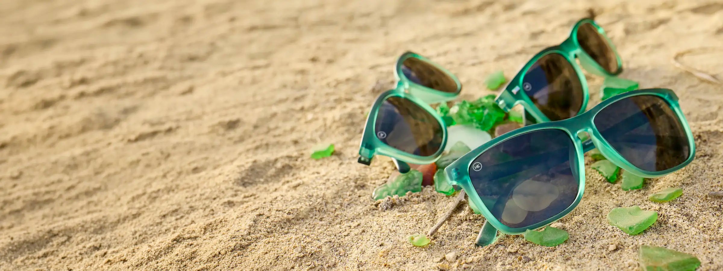 Glass Beach green translucent sunglasses photographed on the beach