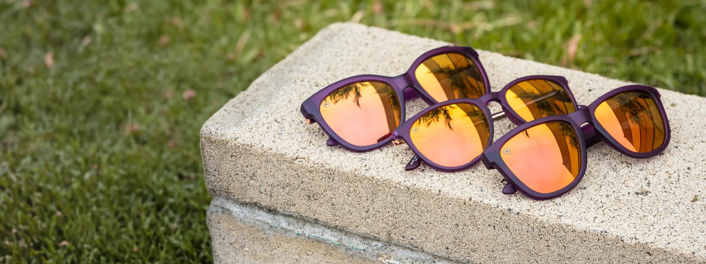 Velvet Royale sunglasses by Knockaround on a ledge over grass