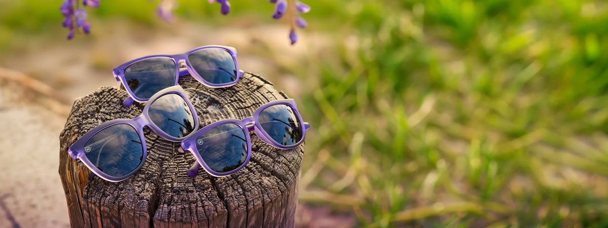 Wisteria sunglasses. 3 pairs of purple sunglasses with smoke lenses photographed on a wooden block in nature