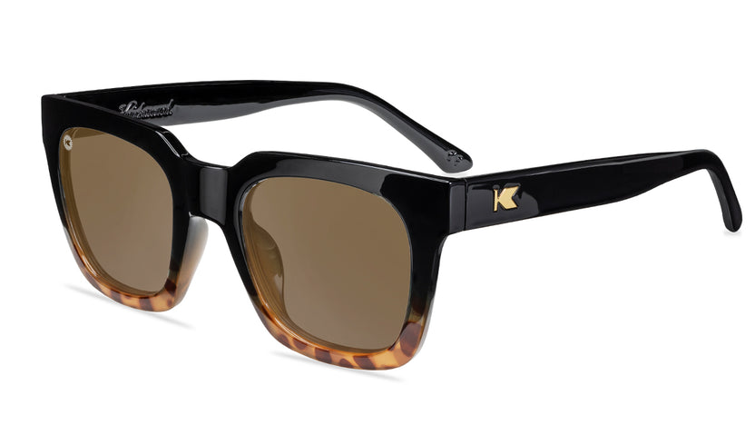 Sunglasses with a glossy black and blonde tortoise shell frame with polarized amber lenses, flyover