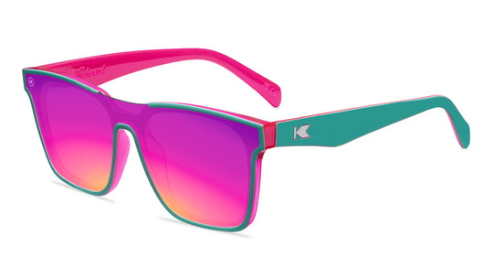 Sunglasses with a teal and pink frame with polarized pink and purple lenses, flyover