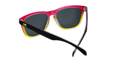 Sunglasses with glossy black frames and polarized pink sunset lenses, back
