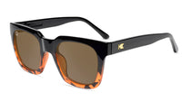 Sunglasses with a glossy black and tortoise shell frame with polarized amber lenses, flyover